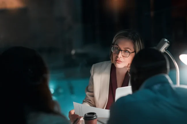 Businesswoman in meeting at night with colleagues.