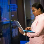 Professional woman using tablet in server room.