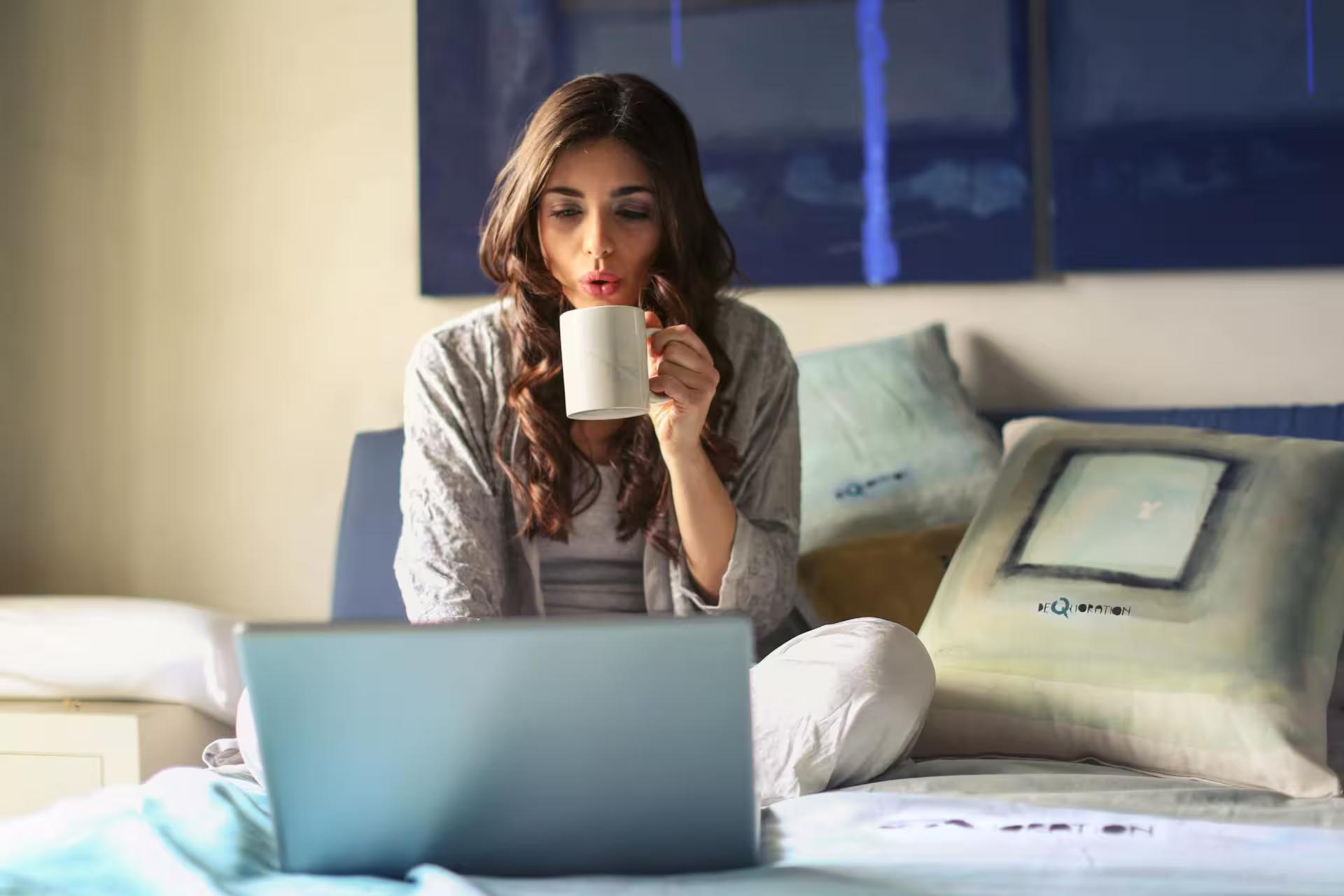 A womon drinking a coffee and working on a laptop.